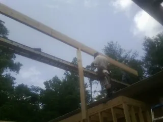 Carpenter setting a ridge beam over a new addition frame — Ice Dam Removal by Roofing Brothers in Cortland